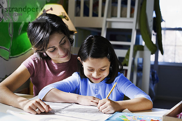 Hispanische Mutter hilft ihrer Tochter bei den Hausaufgaben