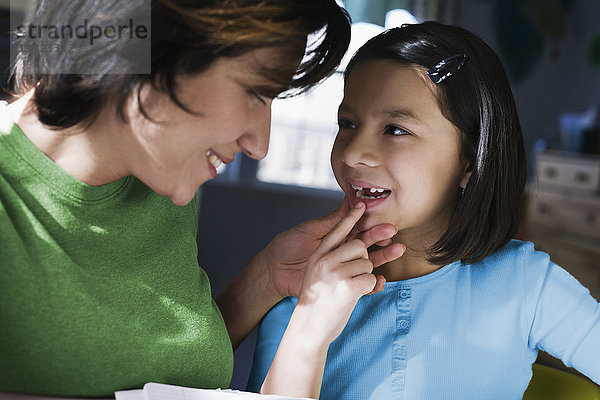 Hispanische Mutter untersucht den fehlenden Zahn ihrer Tochter