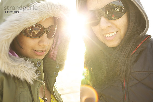 Gemischtrassige Schwestern mit Sonnenbrillen und Kapuzen
