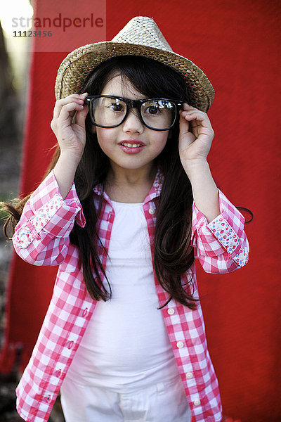Gemischtrassiges Mädchen mit Hut passt die Brille an