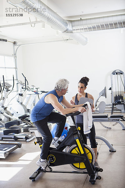 Älterer hispanischer Mann arbeitet mit Trainer im Fitnessstudio