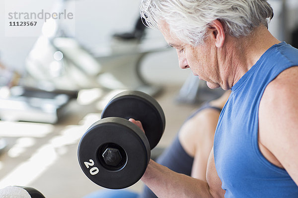 Älterer hispanischer Mann hebt Gewichte im Fitnessstudio