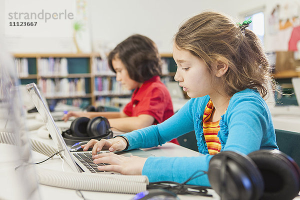 Kaukasische Kinder benutzen Laptops in der Bibliothek