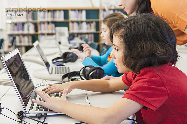 Kaukasische Kinder benutzen Laptops in der Bibliothek