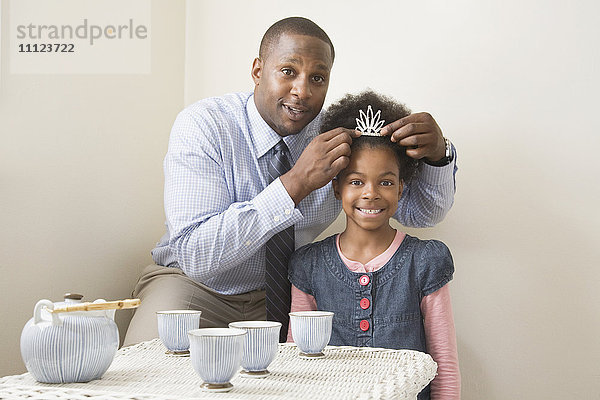 Afrikanischer Vater und Tochter posieren mit Tiara