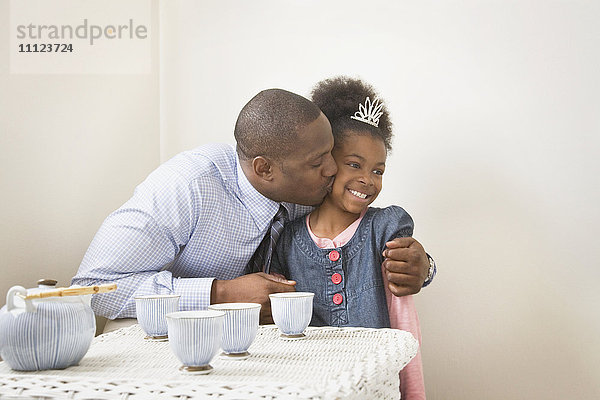 Afrikanischer Vater küsst Tochter mit Diadem
