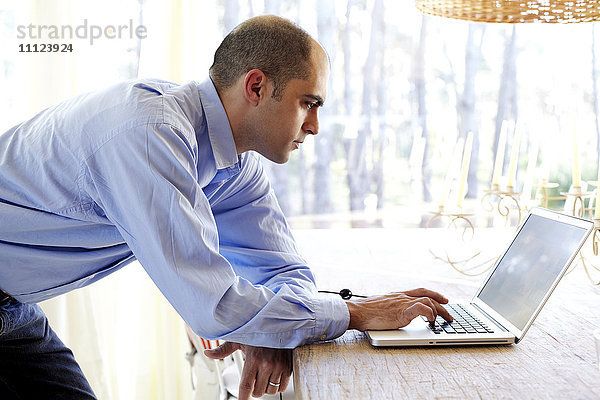 Gemischtrassiger Geschäftsmann benutzt Laptop im Büro