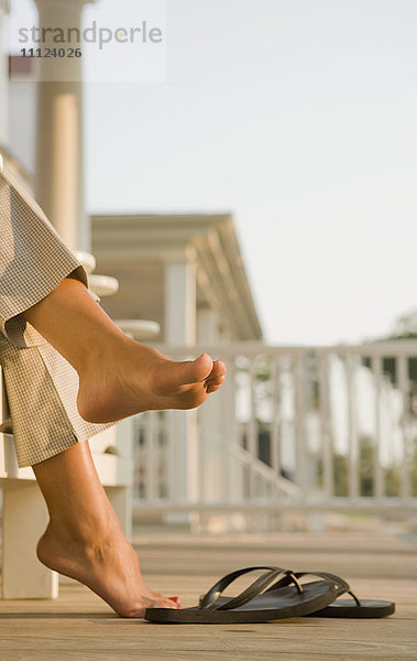 Gemischtrassige Frau barfuß bei Flipflops