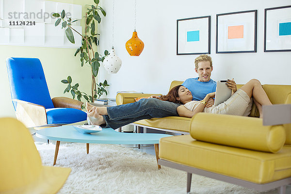 Glückliches Paar entspannt auf Sofa mit digitalem Tablet