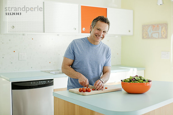 Mann schneidet Gemüse in der Küche