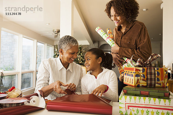 Drei Generationen von Frauen beim Verpacken von Weihnachtsgeschenken