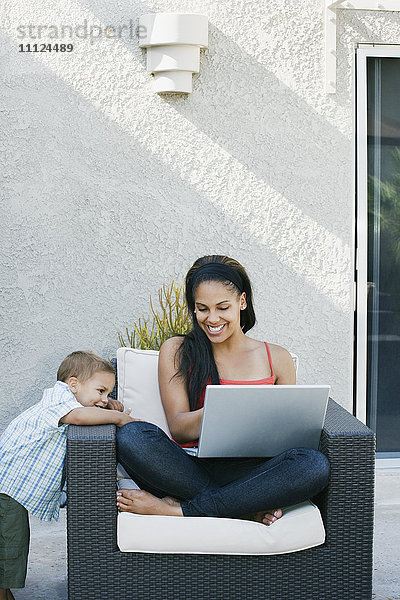 Mutter und Sohn schauen auf einen Laptop auf der Terrasse
