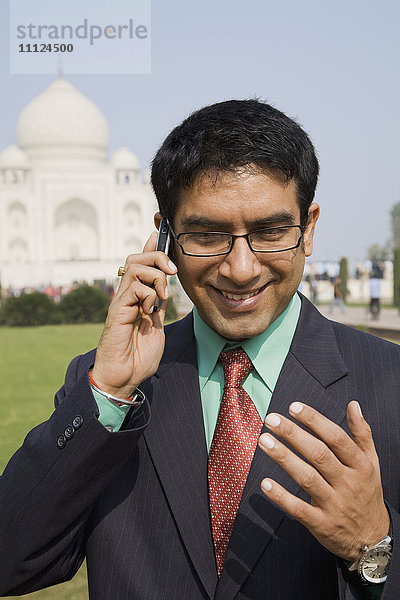 Indischer Geschäftsmann  der am Taj Mahal mit seinem Handy telefoniert