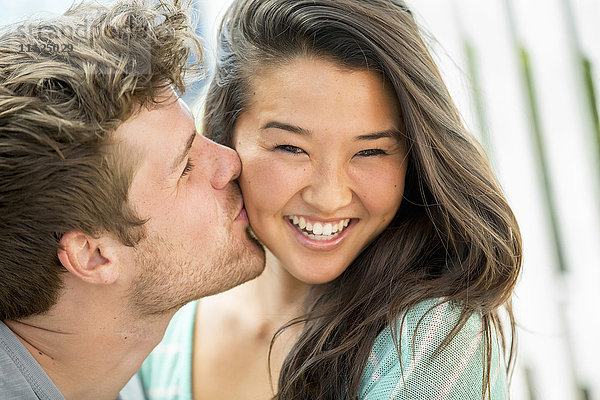 Mann küsst Freundin auf die Wange im Freien
