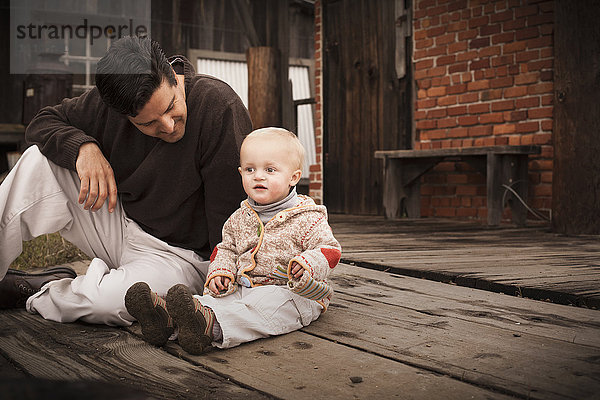 Kaukasischer Vater sitzt mit seinem Sohn auf dem Boden