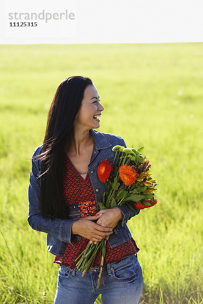 Asiatische Frau hält Blumenstrauß aus Wildblumen