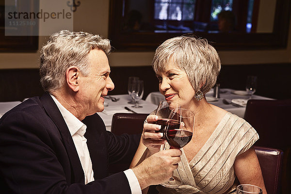 Ehepaar stößt mit Rotwein im Restaurant an