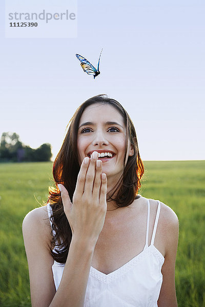 Frau beobachtet Schmetterling auf einer Wiese