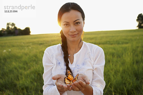 Asiatische Frau hält Schmetterling in den Händen