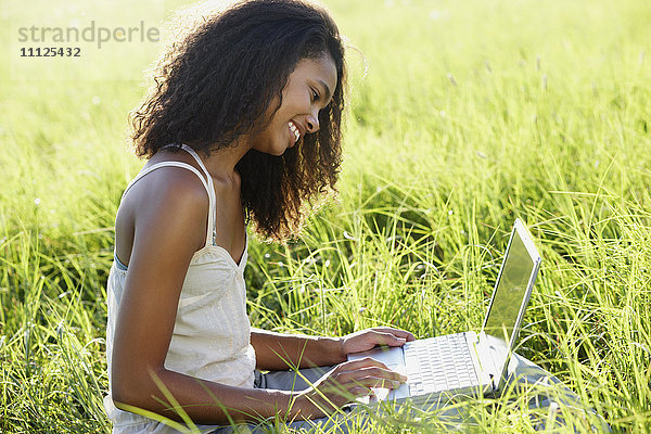 Afrikanische Frau benutzt Laptop auf einer Wiese