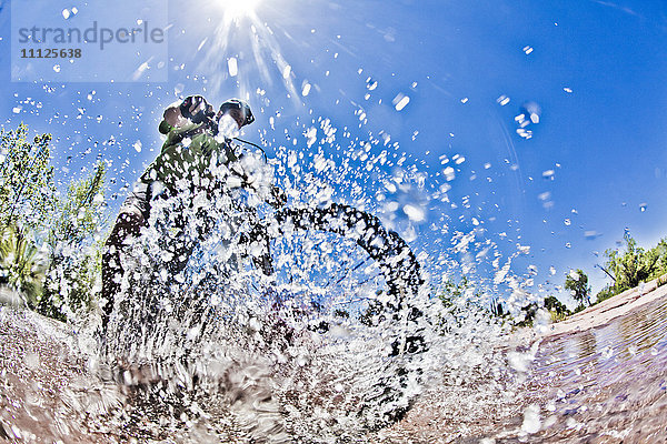 Mann fährt mit dem Mountainbike durchs Wasser