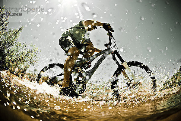 Mann fährt mit dem Mountainbike durchs Wasser