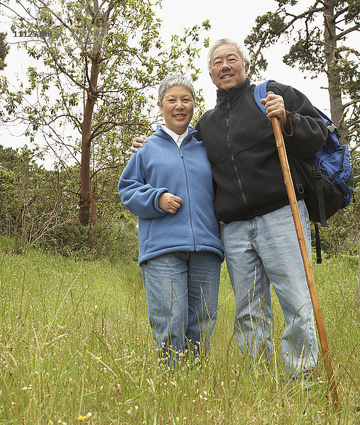 Älteres asiatisches Paar mit Rucksack und Wanderstock im Freien
