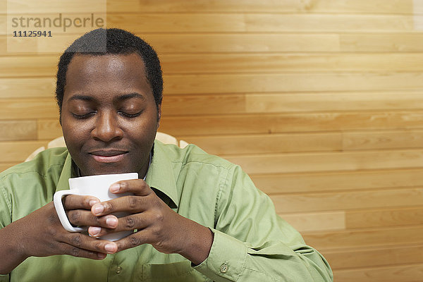 Afrikanischer Mann riecht an einer Tasse Kaffee
