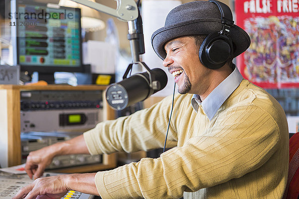 Gemischtrassiger Discjockey mit Plattenspieler im Studio