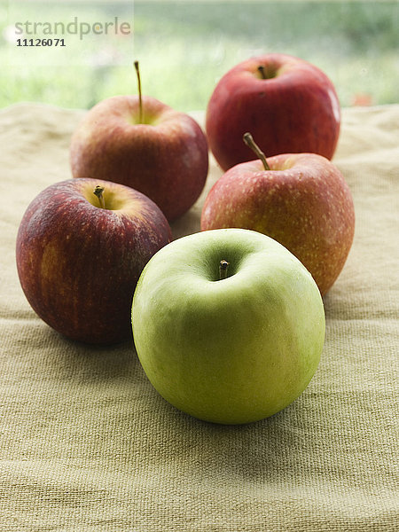 Ein grüner Apfel und vier rote Äpfel