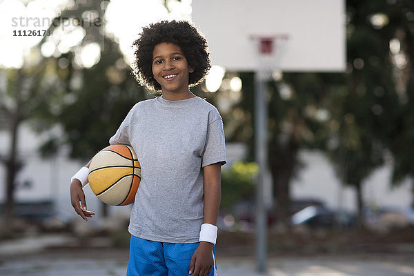 Afroamerikanischer Junge hält Basketball