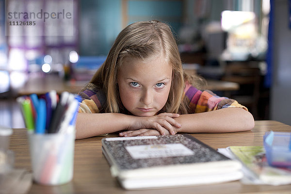 Gelangweiltes kaukasisches Mädchen sitzt im Klassenzimmer