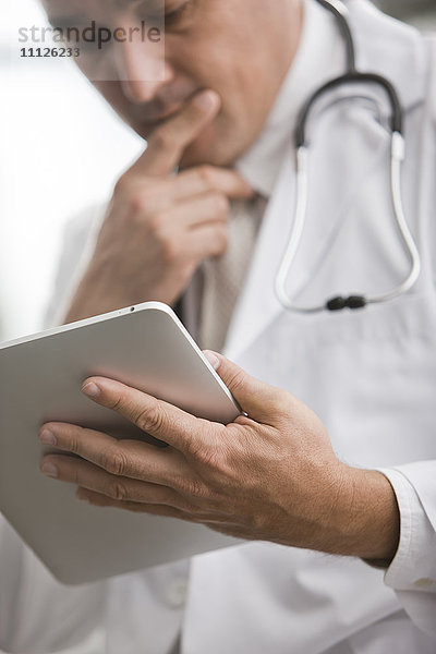 Gemischtrassiger Arzt mit digitaler Tafel