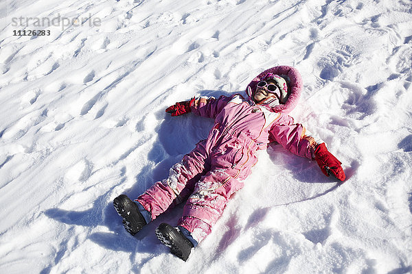 Gemischtrassiges Mädchen macht Schneeengel