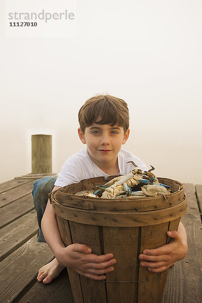 Kaukasischer Junge hält Korb mit Krabben