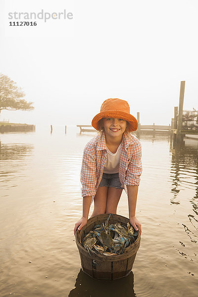 Kaukasisches Mädchen hält Korb mit Krabben