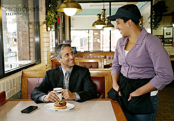 Hispanische Kellnerin im Gespräch mit Geschäftsmann im Restaurant