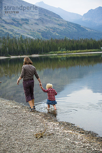 Mutter und Kind gehen in einem stillen ländlichen See spazieren