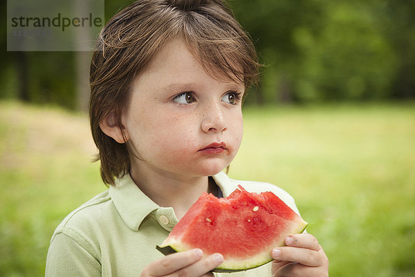 Kaukasischer Junge isst Wassermelone im Freien