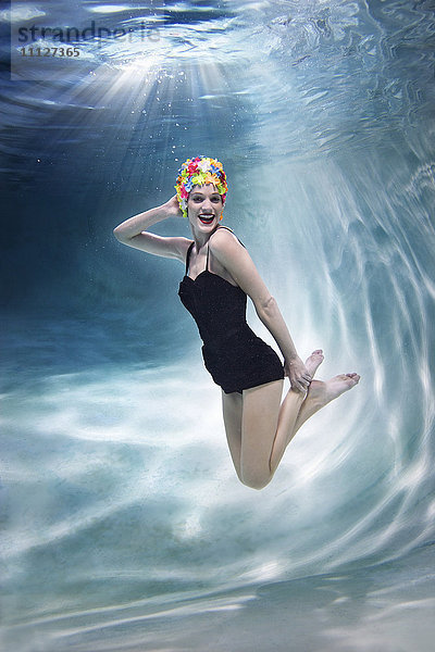 Gemischtrassige Frau schwimmt unter Wasser