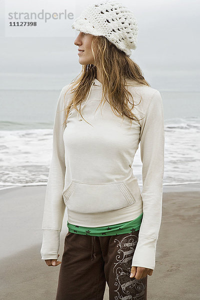 Gemischtrassige Frau mit Hut am Strand