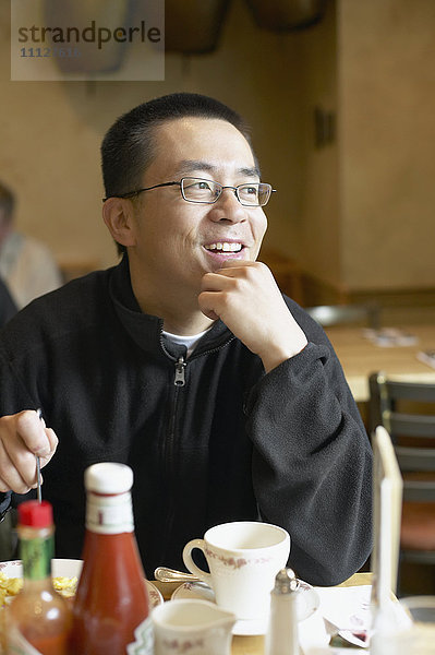 Asiatischer Mann beim Essen im Restaurant