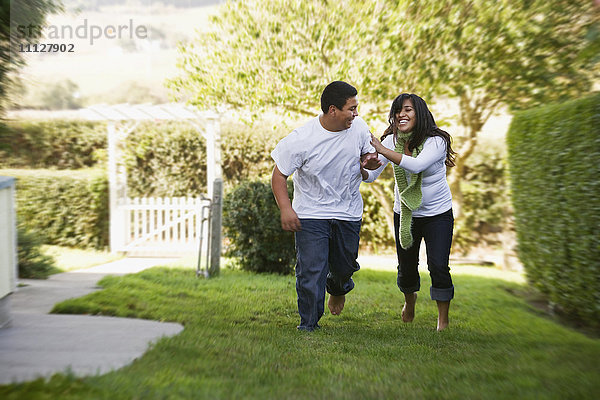 Hispanischer Bruder und Schwester laufen auf Gras