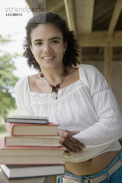 Hispanische Frau stehend mit Lehrbüchern