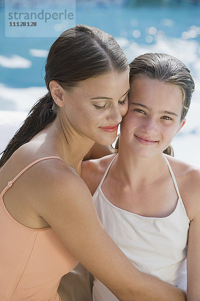Gemischtrassige Frau und Tochter in Badeanzügen  die sich umarmen