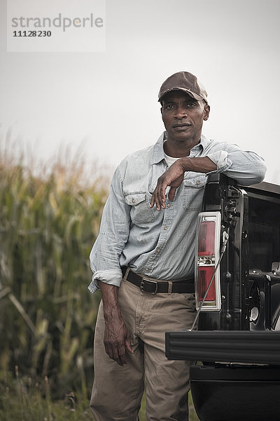 Afroamerikaner lehnt sich an die Rückseite eines Pick-up-Trucks