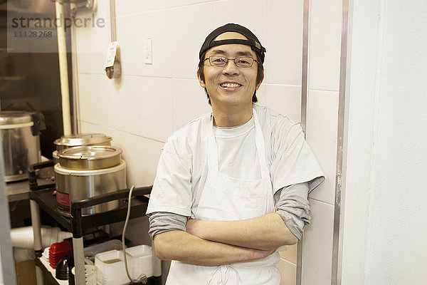 Japanischer Koch lächelt in Großküche