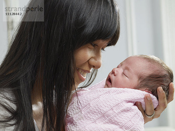 Gemischtrassige Mutter kuschelt mit neugeborenem Baby