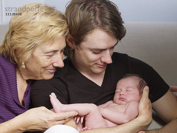 Ältere Mutter und Sohn kuscheln mit neugeborenem Baby