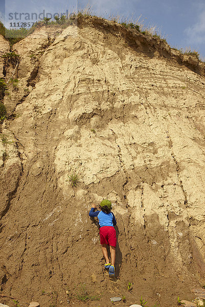 Gemischtrassiger Junge klettert auf schmutzigen Felsen